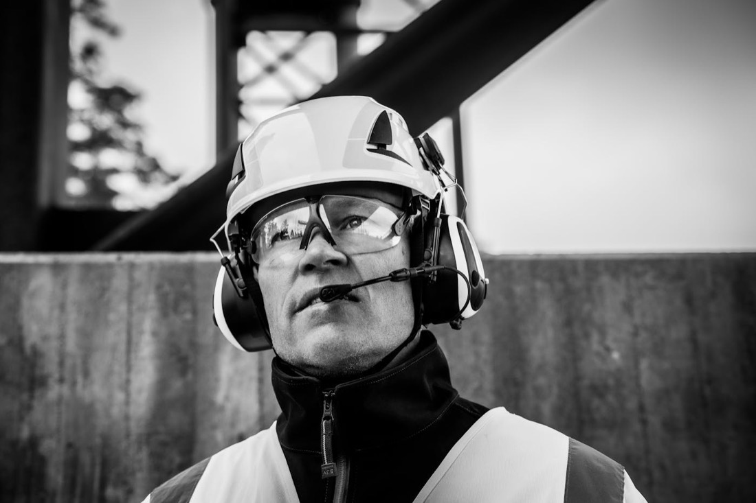 Arbeiter mit Helm, Schutzbrille und Headset in industrieller Umgebung.